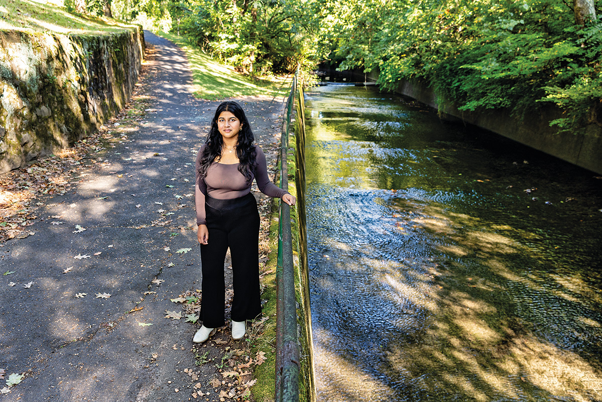 A woman stands on a path near a river