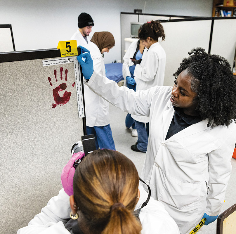 students look for clues in a mock crime scene apartment