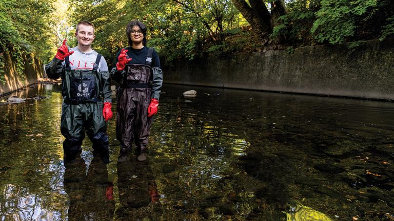 A man and a woman stand in a tributary of the Passaic River
