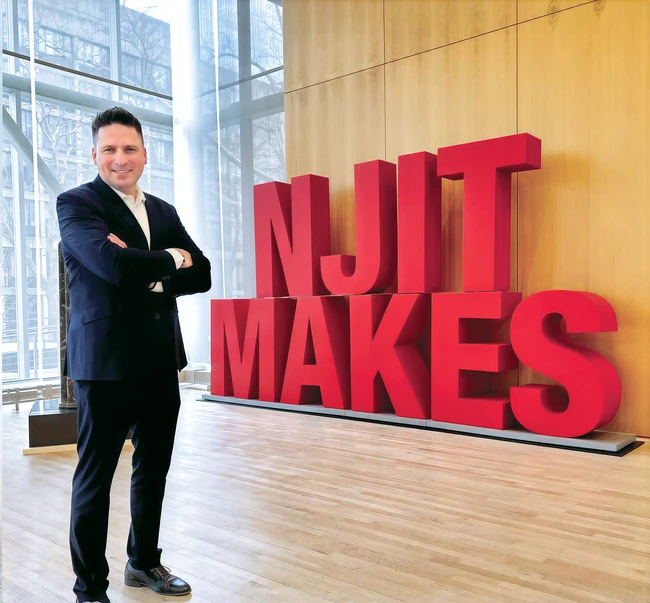 Laszlo Moharita standing in front of the large NJIT MAKES sign